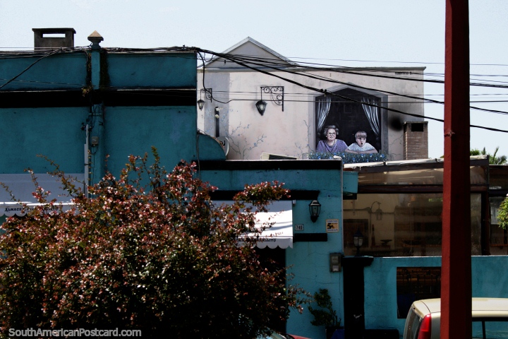 Uma mulher e o rapaz olham para fora uma janela, pintada no lado de uma casa junto de Vigia Praça em Maldonado. (720x480px). Uruguai, América do Sul.