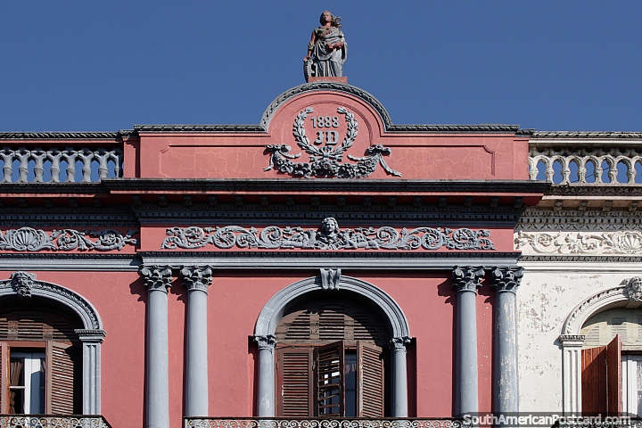 Fachada rosa construida en 1888 con figura prominente en la parte superior y una cara en el medio, Rocha. (720x480px). Uruguay, Sudamerica.