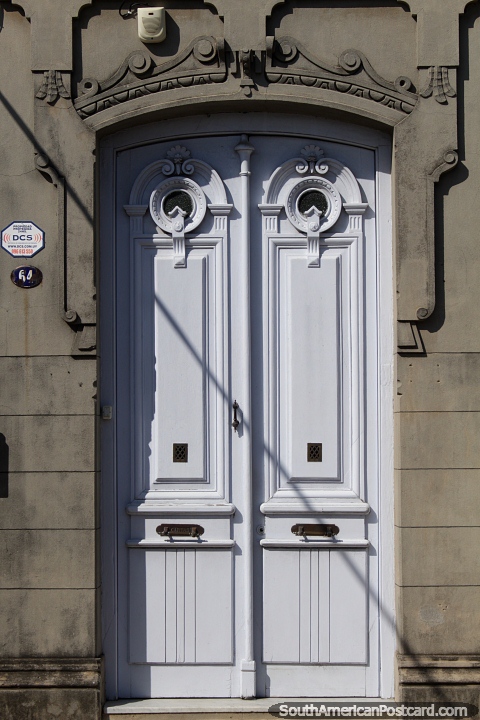 Puerta blanca con un par de ojos de buey en la parte superior, los edificios de Rocha. (480x720px). Uruguay, Sudamerica.