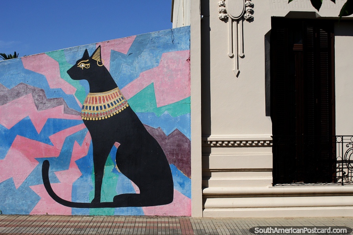 Arte callejero de un gato negro en Rocha junto a una bonita fachada en la calle de la ciudad. (720x480px). Uruguay, Sudamerica.