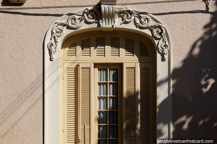 Yellow wooden window shutters beneath an arched facade, a house in Tacuarembo. (720x480px). Uruguay, South America.