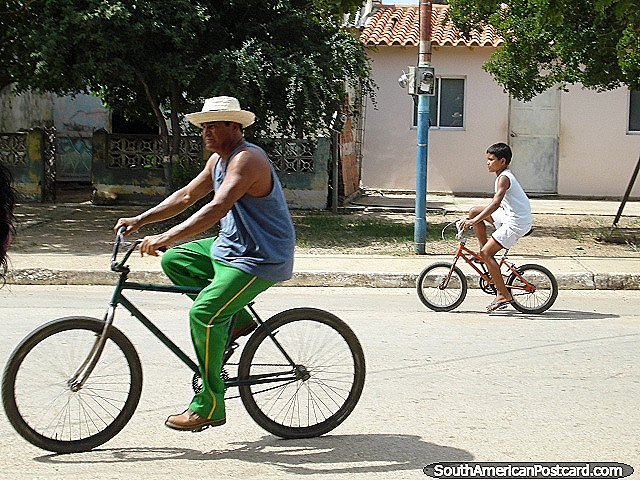 Man and boy ride bicycles in the street in Robledal on Isla Margarita. (640x480px). Venezuela, South America.