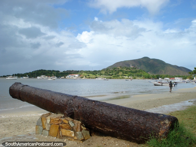 O canhão pela praia em Juan Griego espera os barcos piratas, forte Galera na colina atrás, Ilha Margarita. (640x480px). Venezuela, América do Sul.