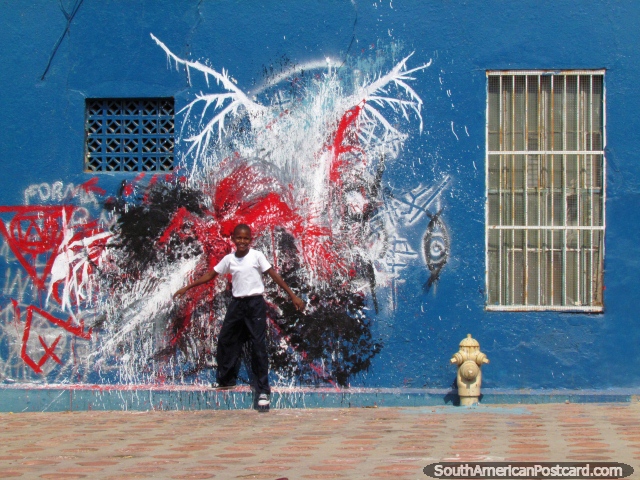 Boy poses for a photo in front of wall graffiti in the Santa Lucia neighbourhood, Maracaibo. (640x480px). Venezuela, South America.