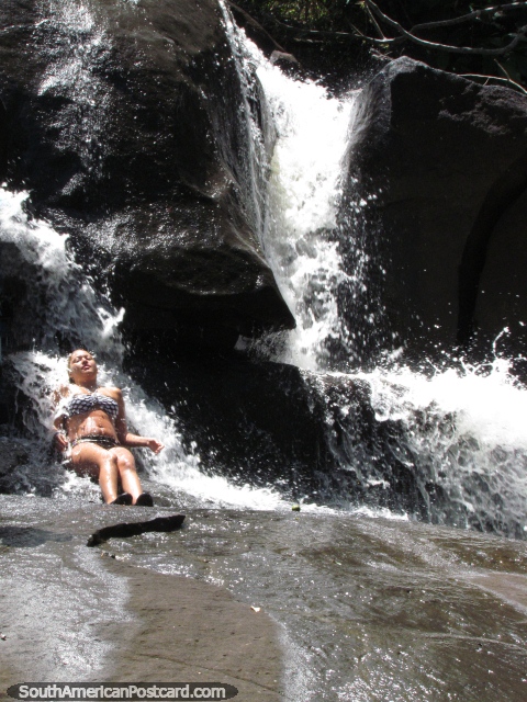 Girl on rocks enjoys the cool waterfall during lunchbreak on the Angel Falls tour. (480x640px). Venezuela, South America.