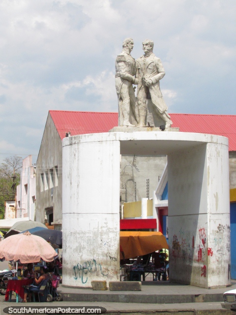 2 men shake hands Bolivar monument near the river in Barcelona. (480x640px). Venezuela, South America.