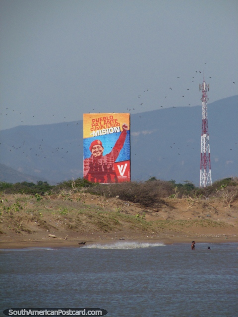 Las aves vuelan por delante de una imagen de la valla publicitaria enorme del Presidente Chavez en la playa de La Vela de Coro en Coro. (480x640px). Venezuela, Sudamerica.