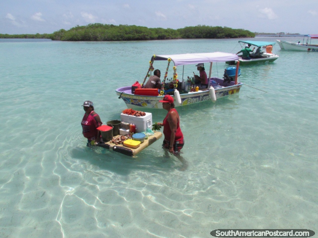 2 women sell fresh seafood from a floating polystyrene board at Cajo Los Juanes, Morrocoy National Park. (640x480px). Venezuela, South America.