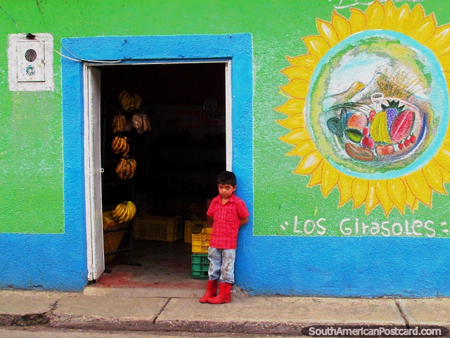 El nio joven en una camisa roja y gumboots est de pie fuera de una tienda de la fruta en Mucuchies. (640x480px). Venezuela, Sudamerica.