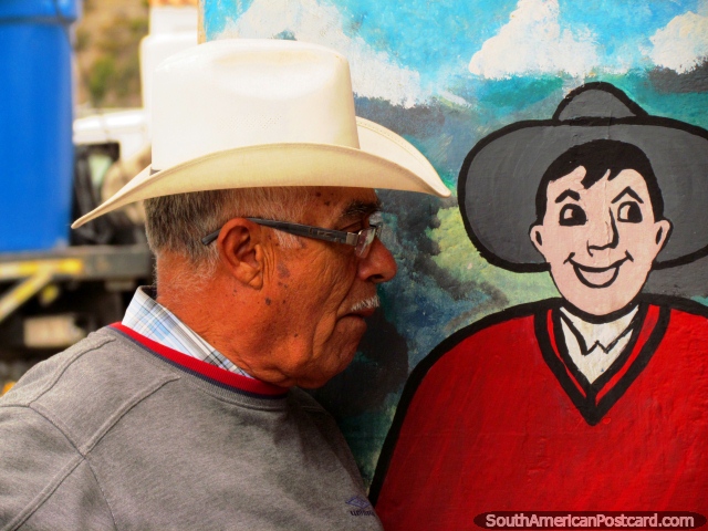 Man stands beside a mural of his younger self in Mucuchies. (640x480px). Venezuela, South America.