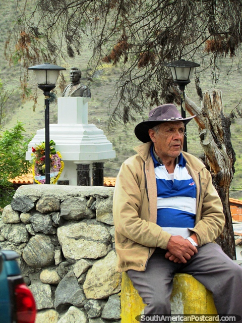 Un hombre local con el sombrero de Mucuchies se sienta al lado de una pared de piedra y la plaza. (480x640px). Venezuela, Sudamerica.
